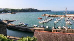 Un port avec des bateaux amarrés, un mur de pierre et une vue sur la côte.