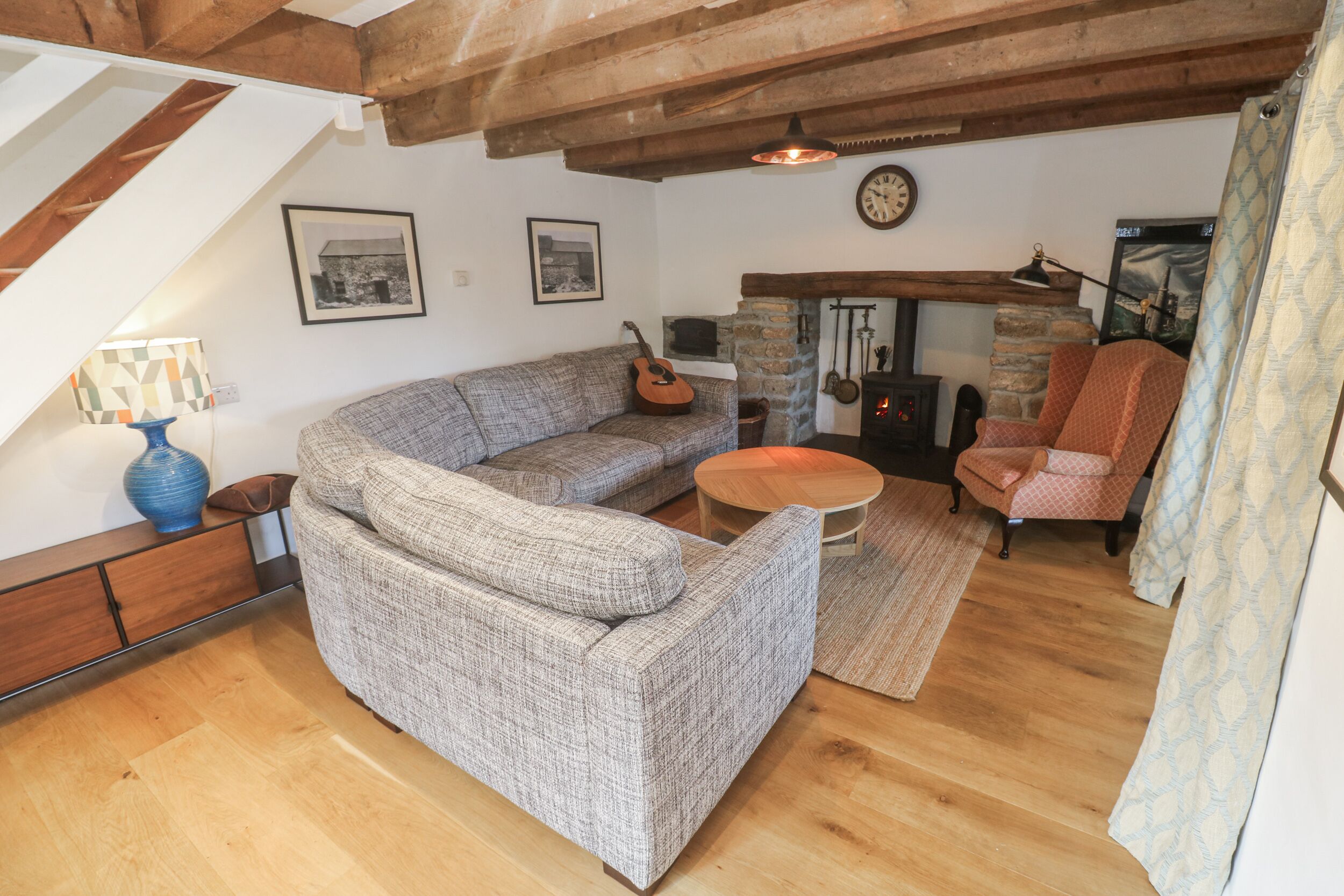 A cozy living room with a sectional sofa, a small round table, a fireplace, and a staircase.