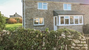 A stone house with two windows and a small porch. - Kernyk (Helston)