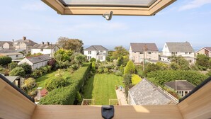 Uitzicht vanuit een kamer met dakraam, op een verzorgde tuin en omliggende huizen.