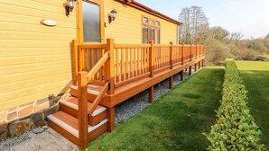 A wooden building with a wooden staircase leading to a deck. - Jules @ 79 (Narberth)