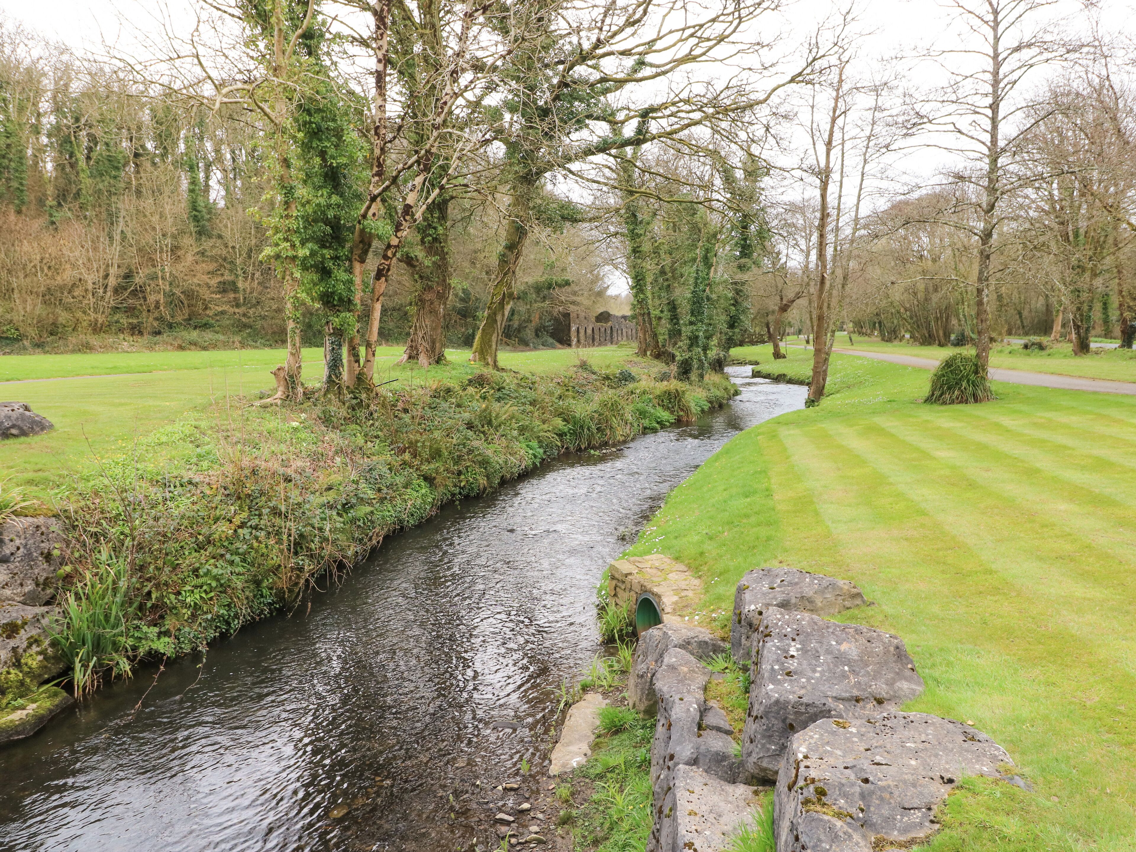 A river flowing through a park with stone walls and trees.