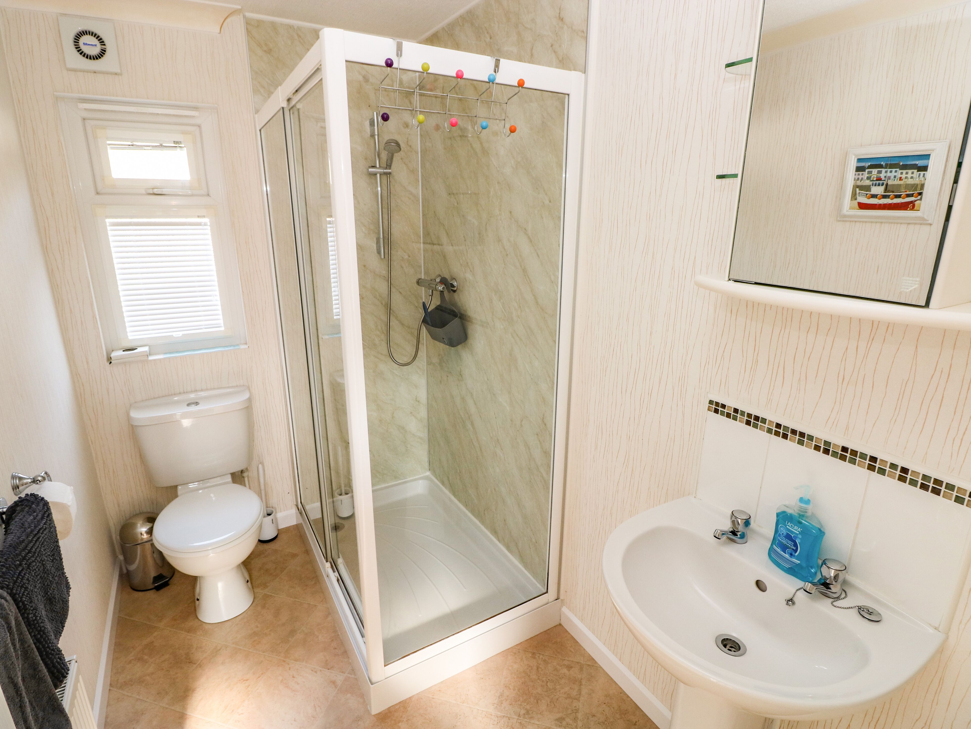 Une salle de bain comprenant des toilettes, une douche avec une porte en verre, un lavabo et un miroir.