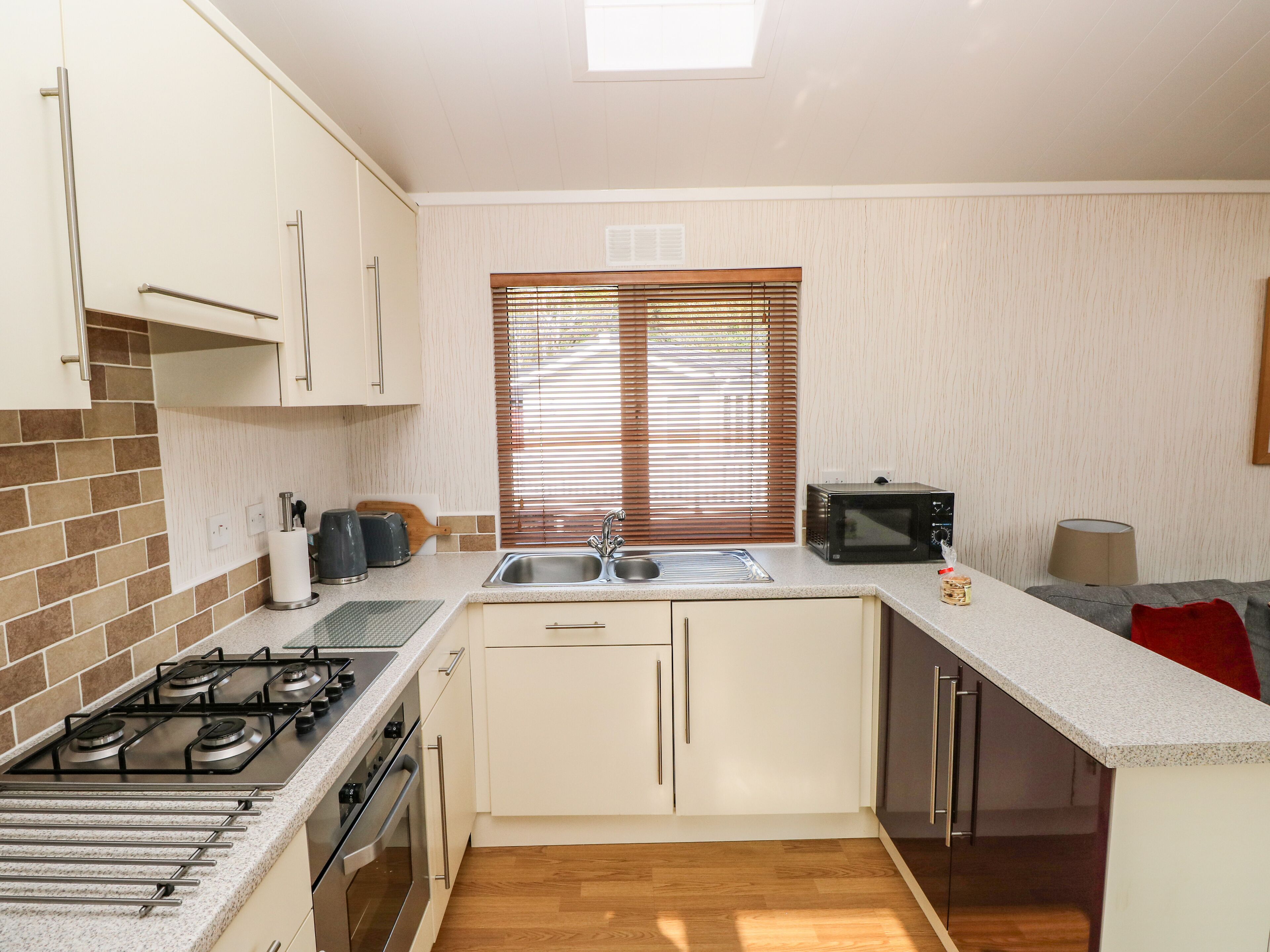 A compact kitchen with a gas stove, oven, microwave, and a sink.