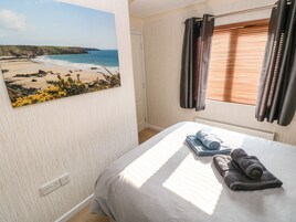 Un dormitorio con una pintura de vista al mar, una cama con toallas enrolladas y una ventana con persianas.