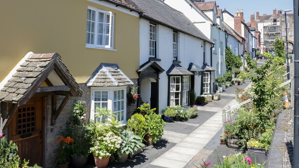 A narrow street lined with traditional houses, each with distinct architectural features like pitched roofs and white window frames. - Alders View Coach House (Craven Arms)
