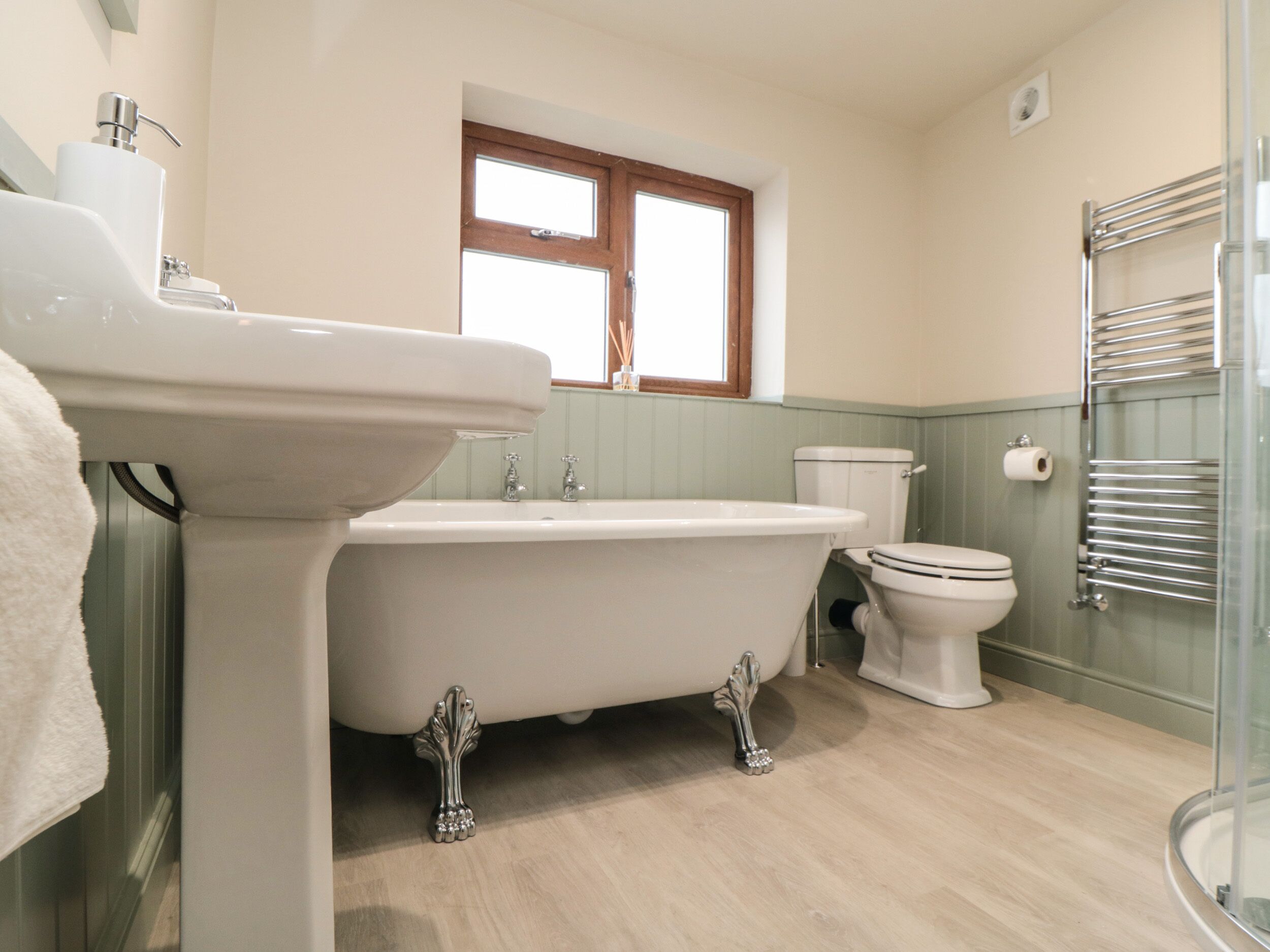 Ein Badezimmer mit freistehender Badewanne, Waschbecken, Toilette und einer Duschkabine aus Glas.