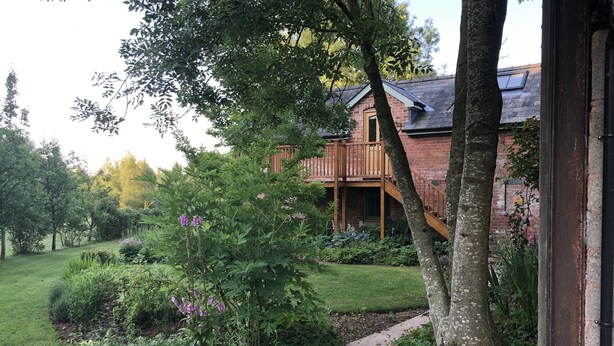 Ein Ziegelhaus mit einer Holzdielen-Terrasse und einem Steinweg, der dorthin führt.