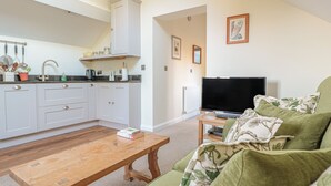 Ein Wohnzimmer mit Couch, Fernseher auf Holzfuß und Couchtisch aus Holz.