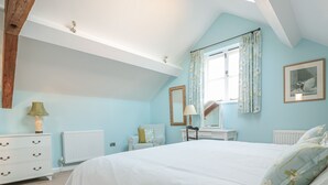 Ein Schlafzimmer mit einem großen Bett, einem Schminktischchen, einem Schreibtisch, einem Stuhl und einer Heizung.
