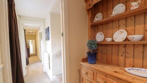 A wooden cabinet with dishes and a potted plant. - Turret Cottage (Prestonpans)