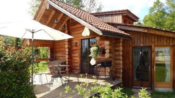 A log cabin with a patio area, outdoor seating, and a large umbrella. - Cozy Log Chalet with Terrace, Near Alsace and Ski Resorts (Le Saulcy)