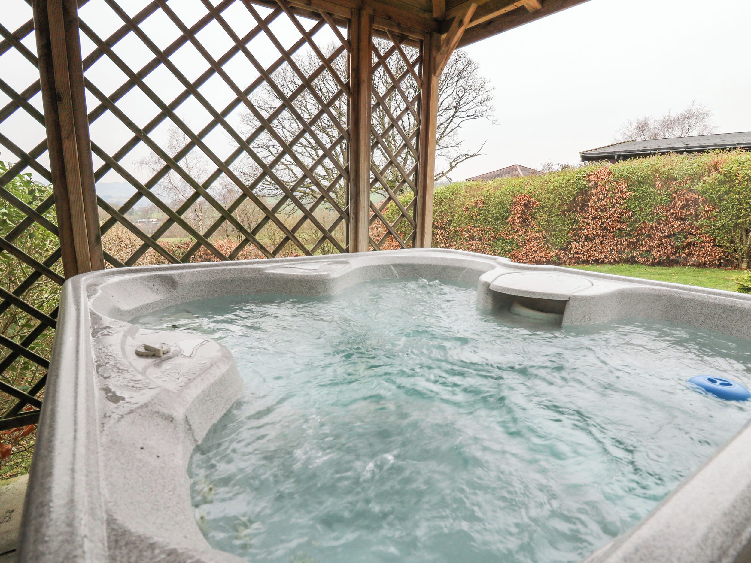 A hot tub in a covered outdoor area with a wooden lattice structure.