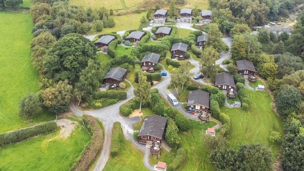 Vue aérienne d’un quartier résidentiel avec de nombreuses maisons, des routes et des champs verdoyants.