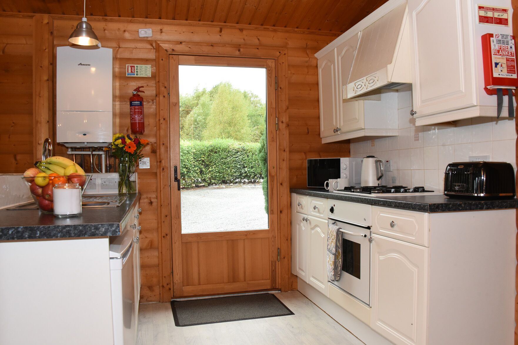 A compact kitchen with white cabinets, a microwave, a toaster, and a gas stove.