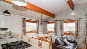 Een kleine keuken met een gasfornuis, een eethoek met een tafel en stoelen, en een leren bank.