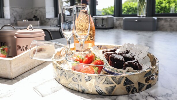 A breakfast tray with strawberries, a bottle of champagne, and chocolate desserts on a marble countertop. - Ysgubor Tyddyn Isaf (Corwen)