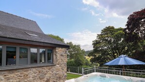 A stone house with a hot tub and a blue umbrella. - Ysgubor Tyddyn Isaf (Corwen)