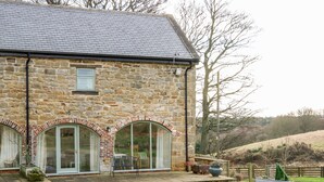A stone house with a gravel driveway, large windows, and a small porch area. - Bowes Barn (Gateshead)
