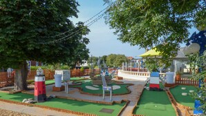 A miniature golf course with a lighthouse, wooden fences, and a small pond. - The Yatt (Colwyn Bay)