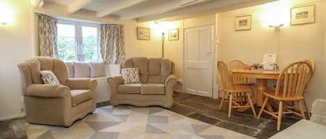 A cozy living room with a sofa set, a dining table with chairs, and a patterned rug.