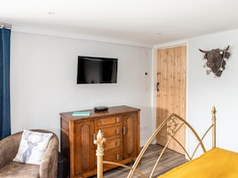 A room with a wooden cabinet, a television mounted on the wall, a bed with a metal frame, and a decorative wall piece.