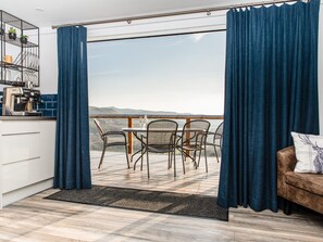 A modern kitchen with a coffee machine, a dining area with a table and chairs, and a view of the hills. - Haka Lodge (Aberystwyth)