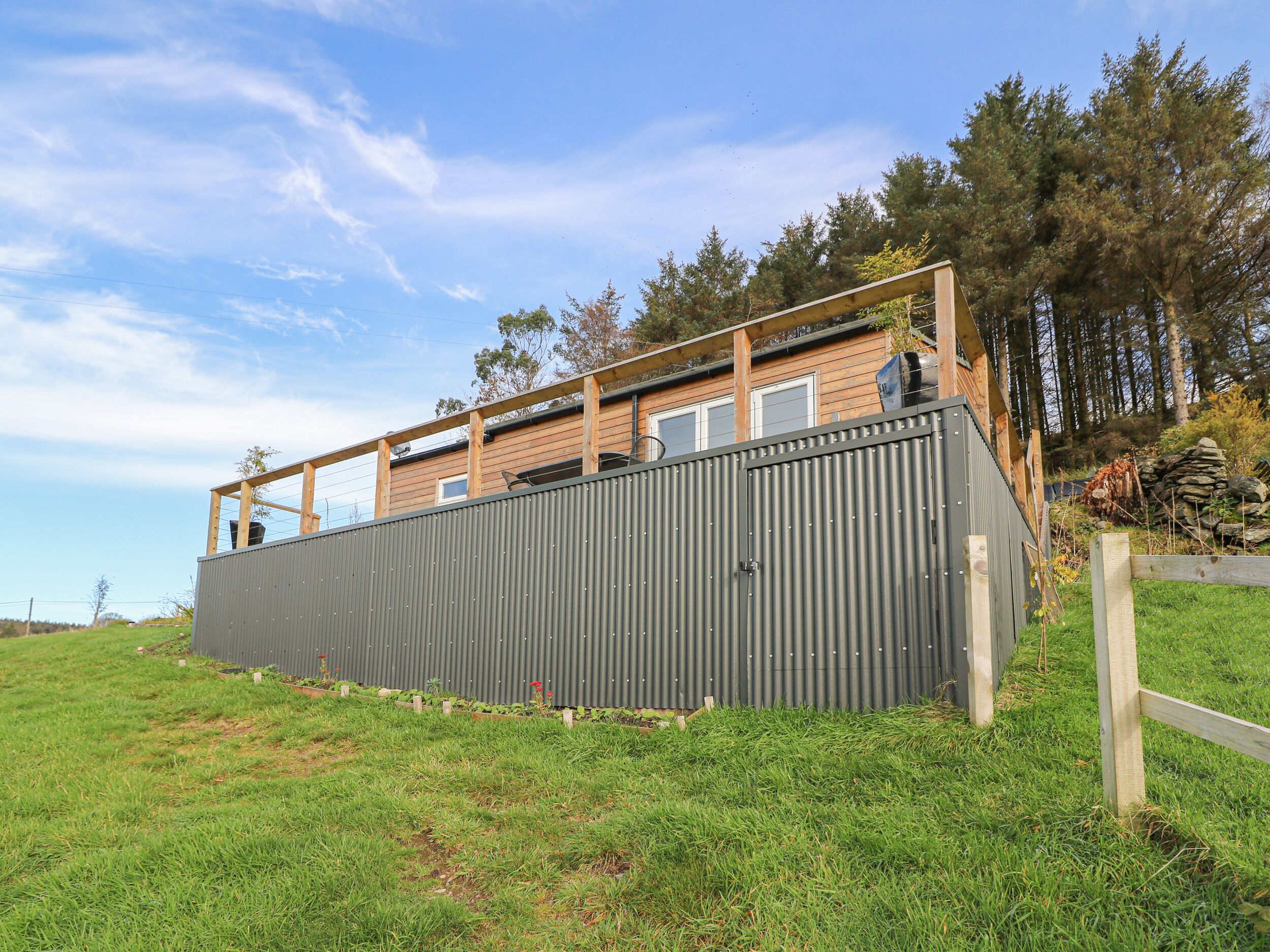 A modern building with a flat roof and a large grey metal wall.