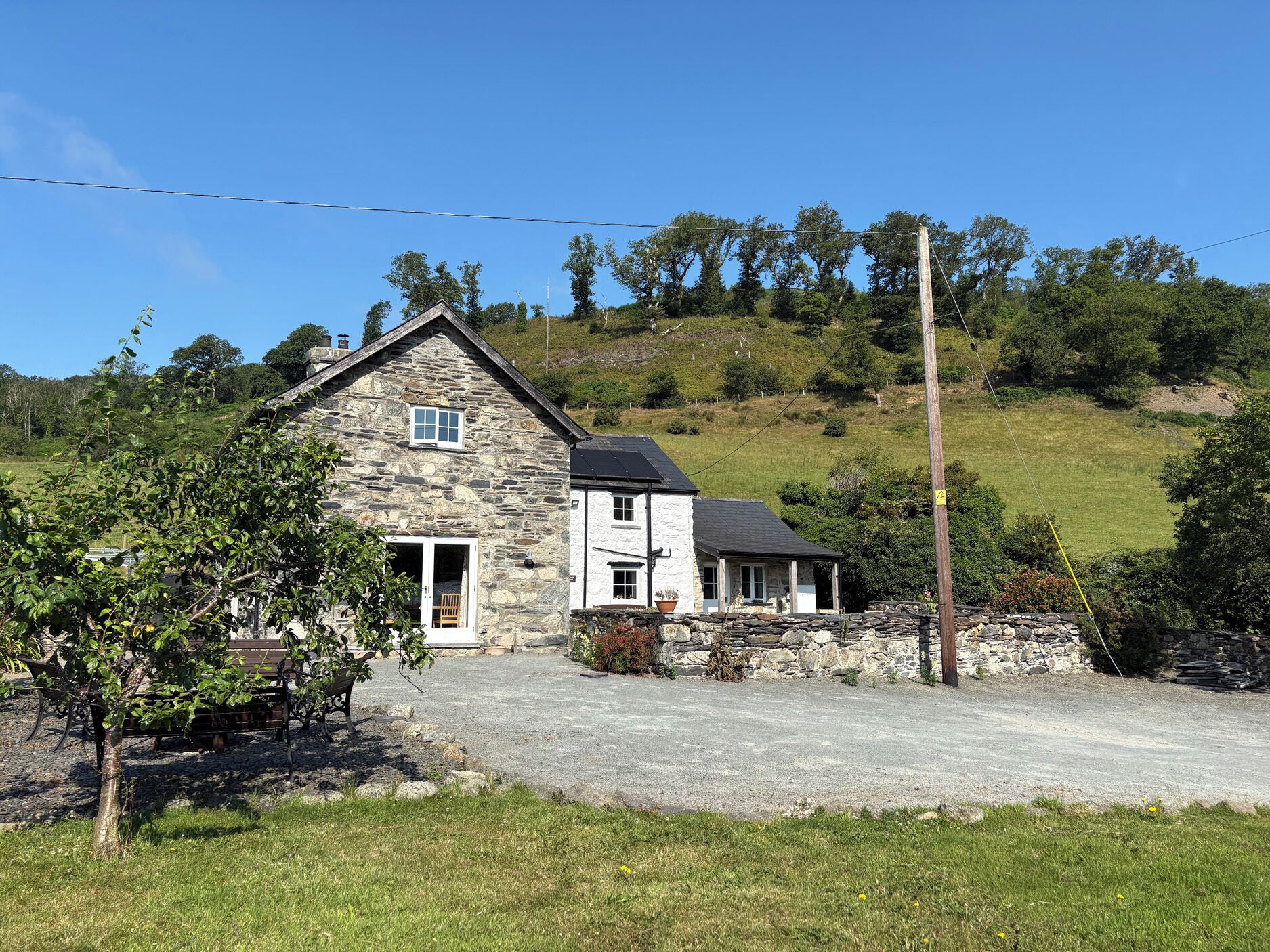 A stone house with a two-story structure, a front porch, and a gravel driveway.