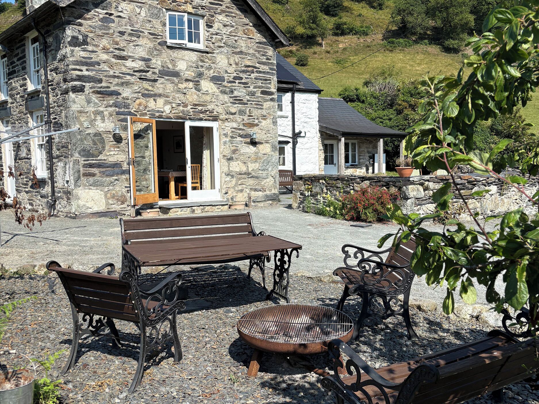 A stone house with a patio area featuring a wooden table and two benches.