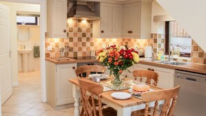 A kitchen with a dining table, chairs, and a vase of flowers.