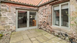 A stone building with a tiled roof, a glass door, and a window. - The Old Workshop (Belford)