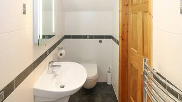Une salle de bain avec un lavabo blanc, des toilettes et une porte en bois.