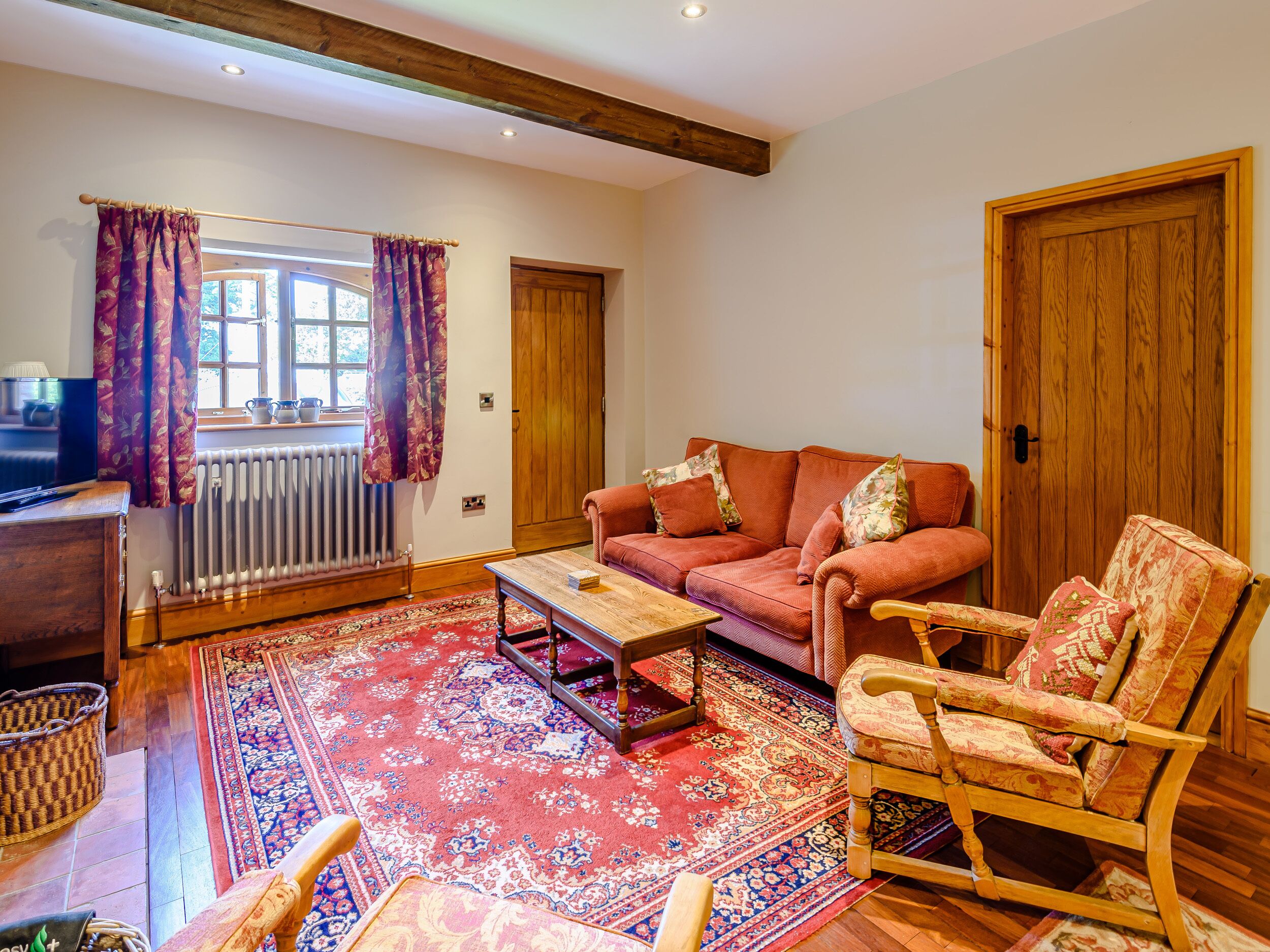 A cozy living room with a sofa, a rocking chair, a coffee table, and a large patterned rug.