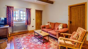 A cozy living room with a sofa, a rocking chair, a coffee table, and a large patterned rug.