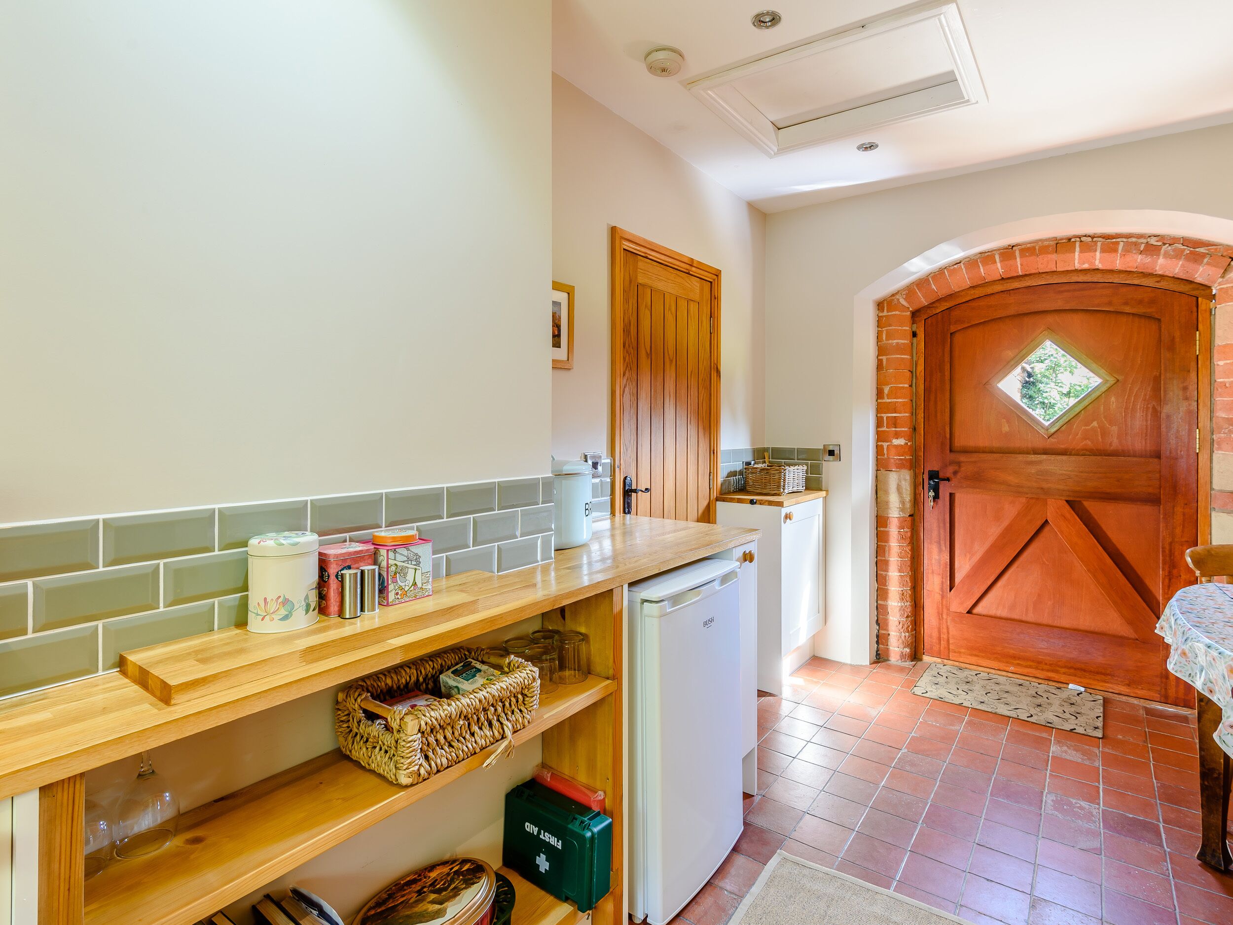 A kitchen with a wooden countertop, a white refrigerator, and a brick oven door.