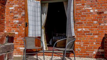A brick building with an open doorway and two wicker chairs outside.