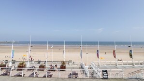 Une promenade en bord de mer avec une jetée, des espaces aménagés pour s’asseoir et des drapeaux.