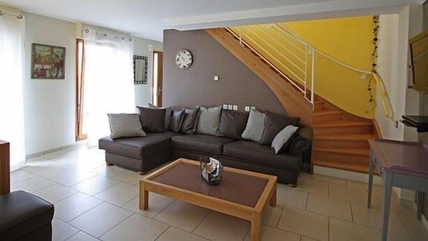 A living room with a sofa, coffee table, and a staircase with a yellow railing.