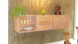 A wooden cabinet with a green plant, a green vase, and a wooden sculpture.