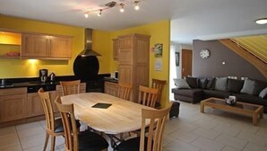 A compact living space with a dining area, kitchen, and a sofa in the living room.