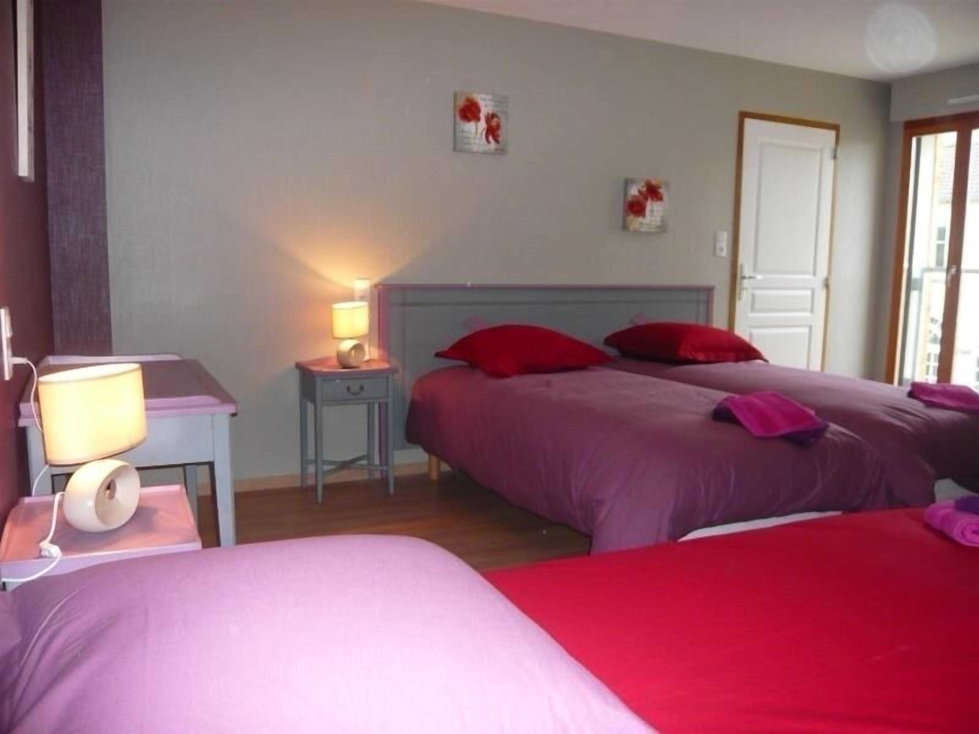 A bedroom with two beds, a bedside table with a lamp, and a wall-mounted picture.