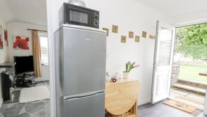A modern kitchen with a built-in microwave, a wooden sideboard, and a door leading to a balcony. - Halcyon Annexe (Moelfre)