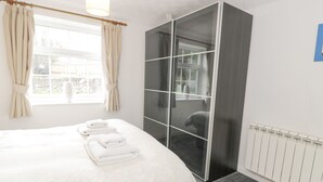 A hotel room with a bed, a large mirror, and a view of the outdoors through a window. - Halcyon Annexe (Moelfre)
