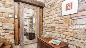 A stone-walled hallway with a wooden bench, a wooden cabinet, and a framed picture on the wall. - The Boot Room (Preston)