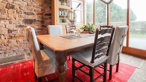 A dining area with a stone wall, wooden table, and chairs. - The Boot Room (Preston)