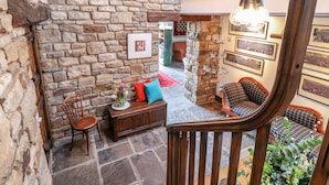 A cozy room with stone walls, a wooden staircase, and a seating area with cushions and a small table. - The Boot Room (Preston)