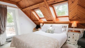 Ein Schlafzimmer mit einem großen Bett, Holzbalkendecke und Dachfenstern.