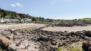 Ein felsiger Strand mit Häusern im Hintergrund.