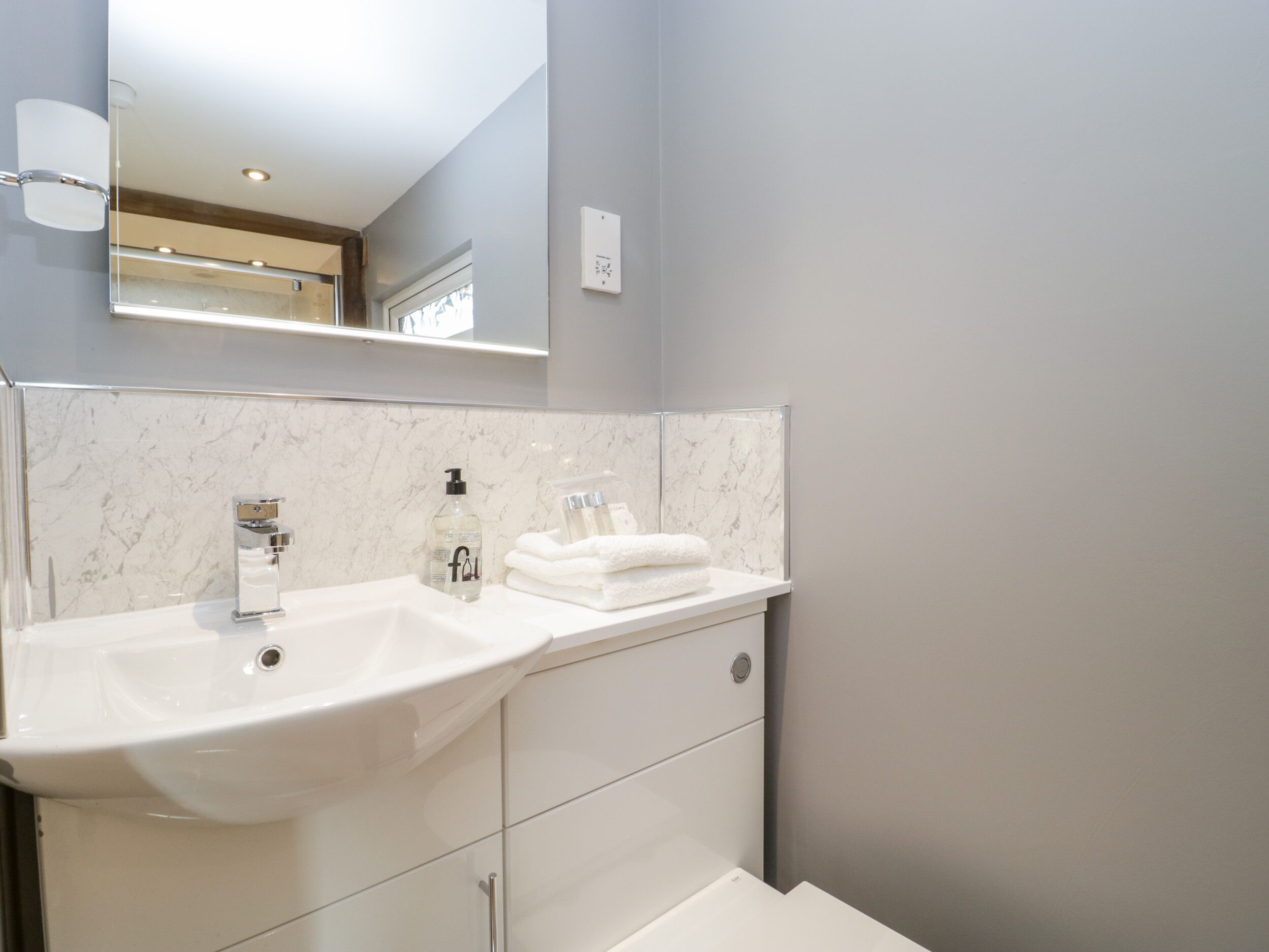 A bathroom with a white sink, a mirror, and a towel rack.